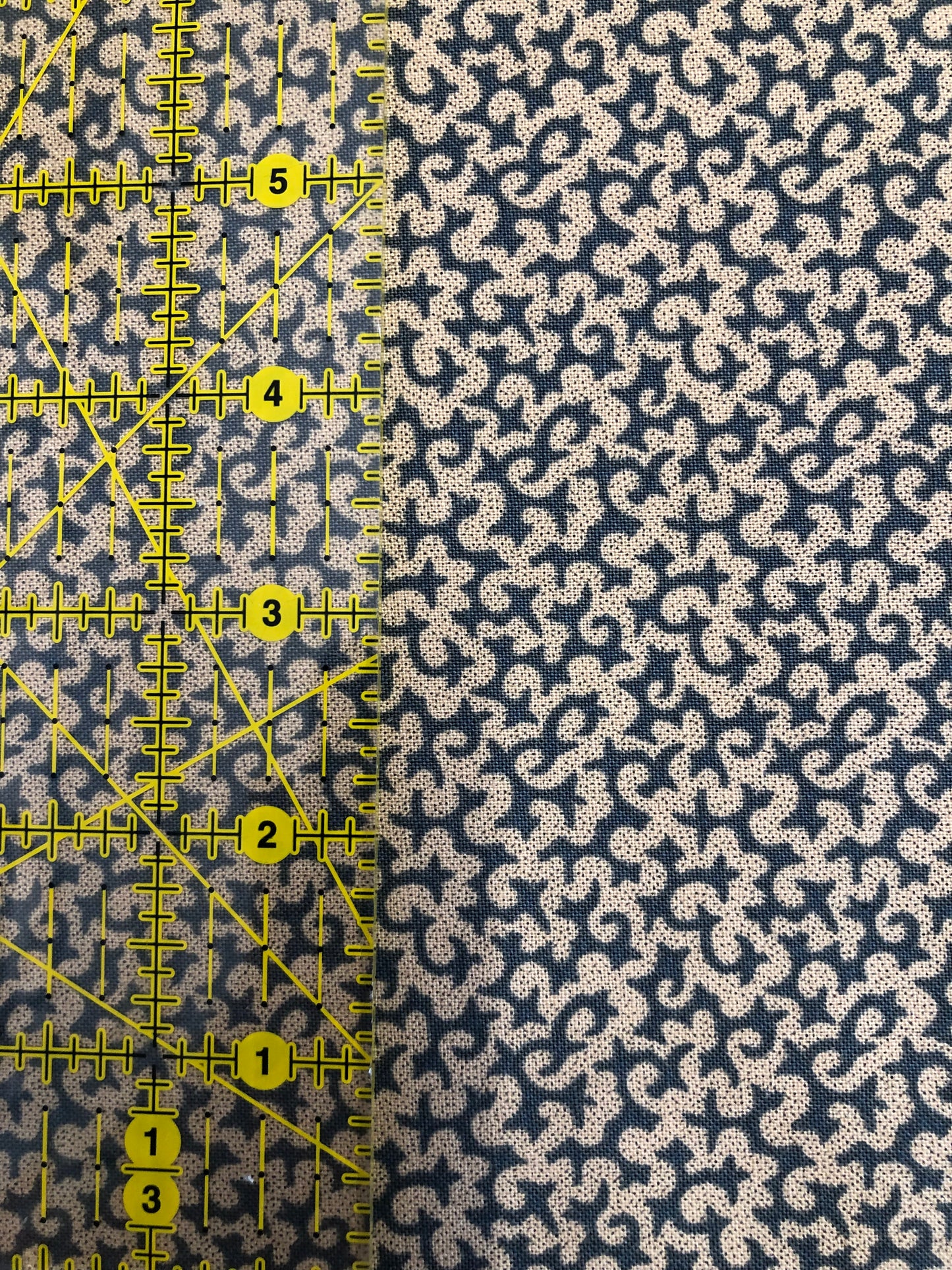 Jo Morton fabric, cream squiggles on navy blue, beside a ruler in inches