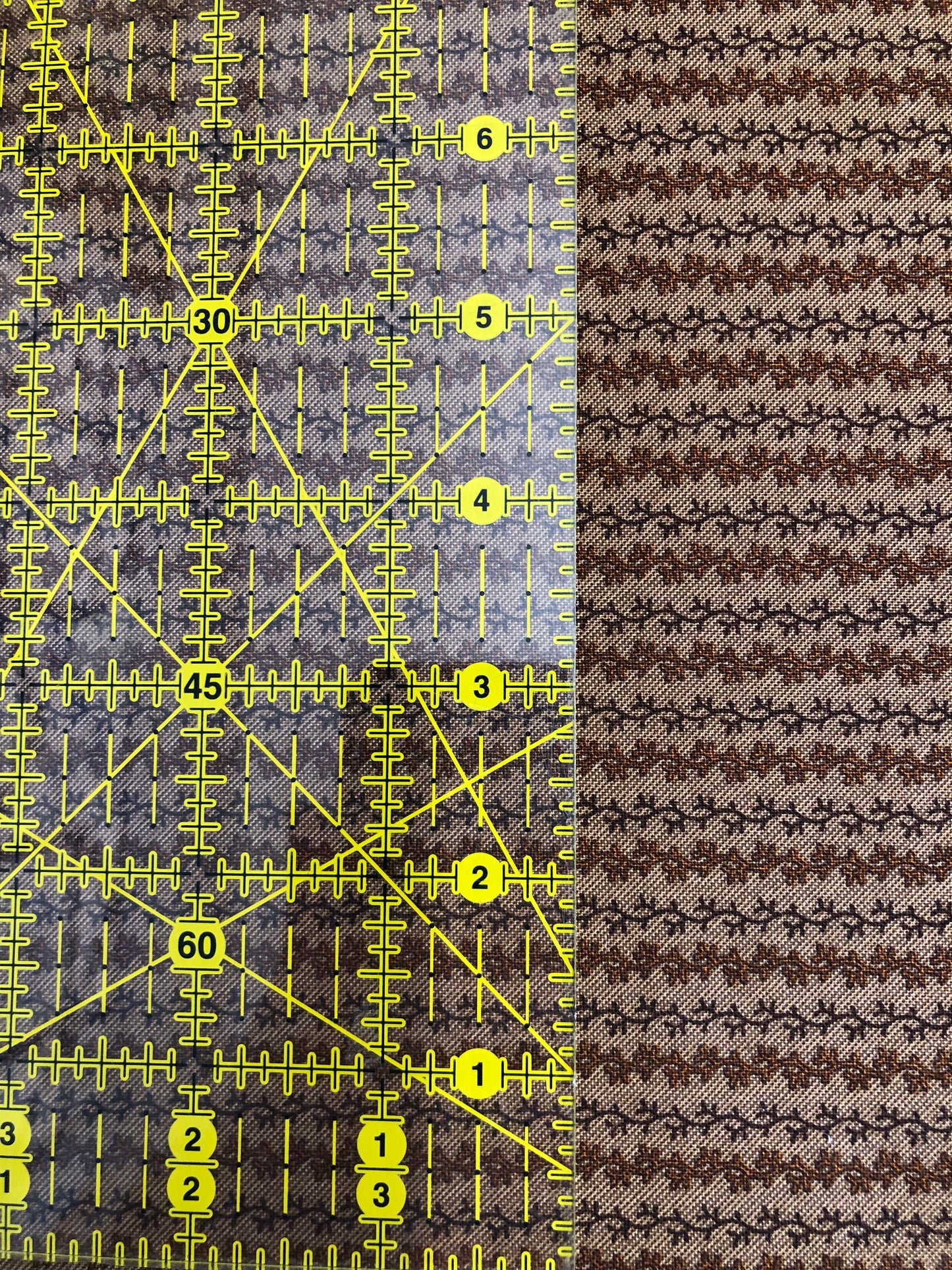 Jo Morton fabric, rows of small brown leafy vines on a pale ground, beside a ruler in inches