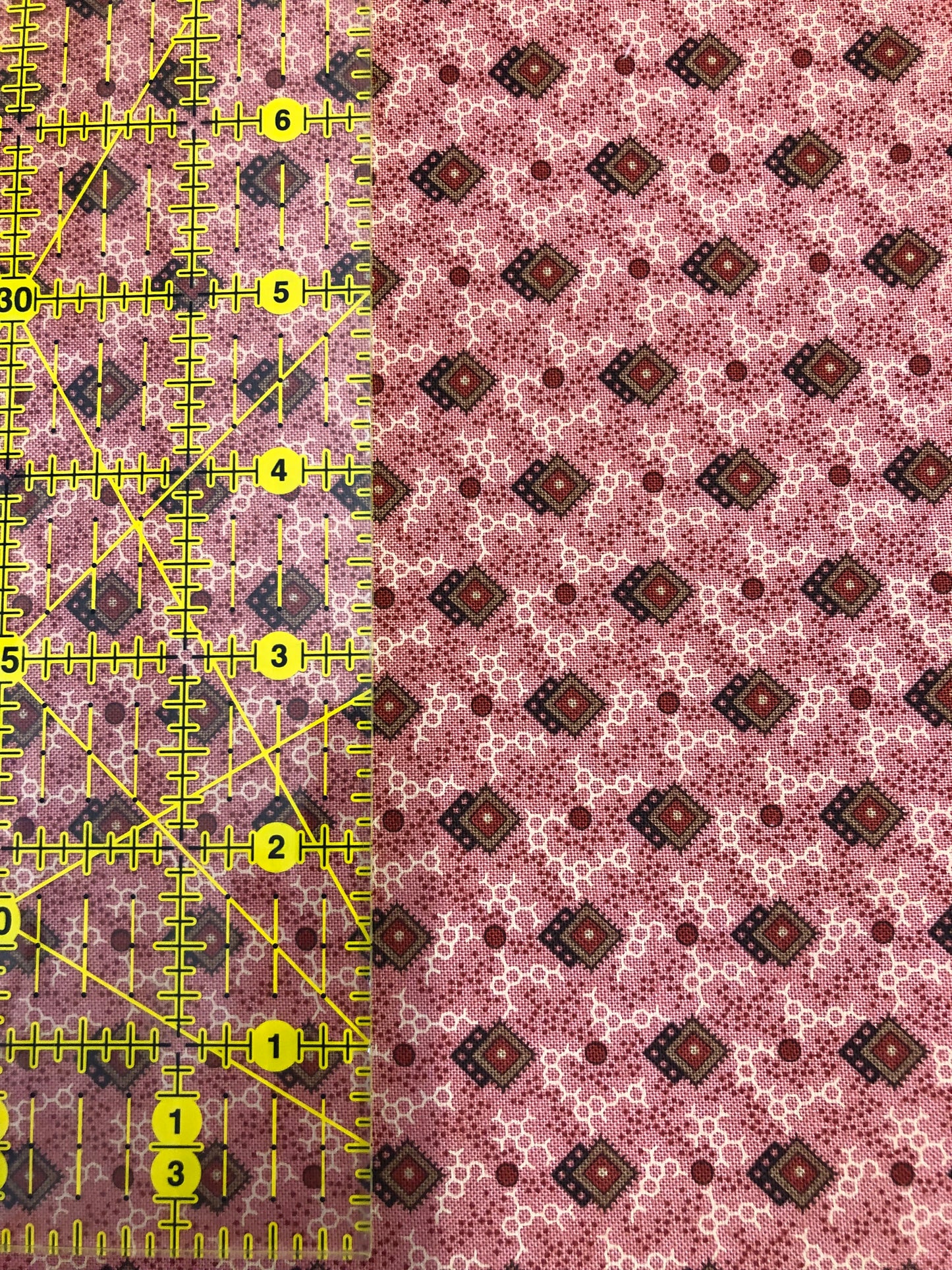 Jo Morton fabric, small brown diamonds and dots on pink, beside a ruler in inches