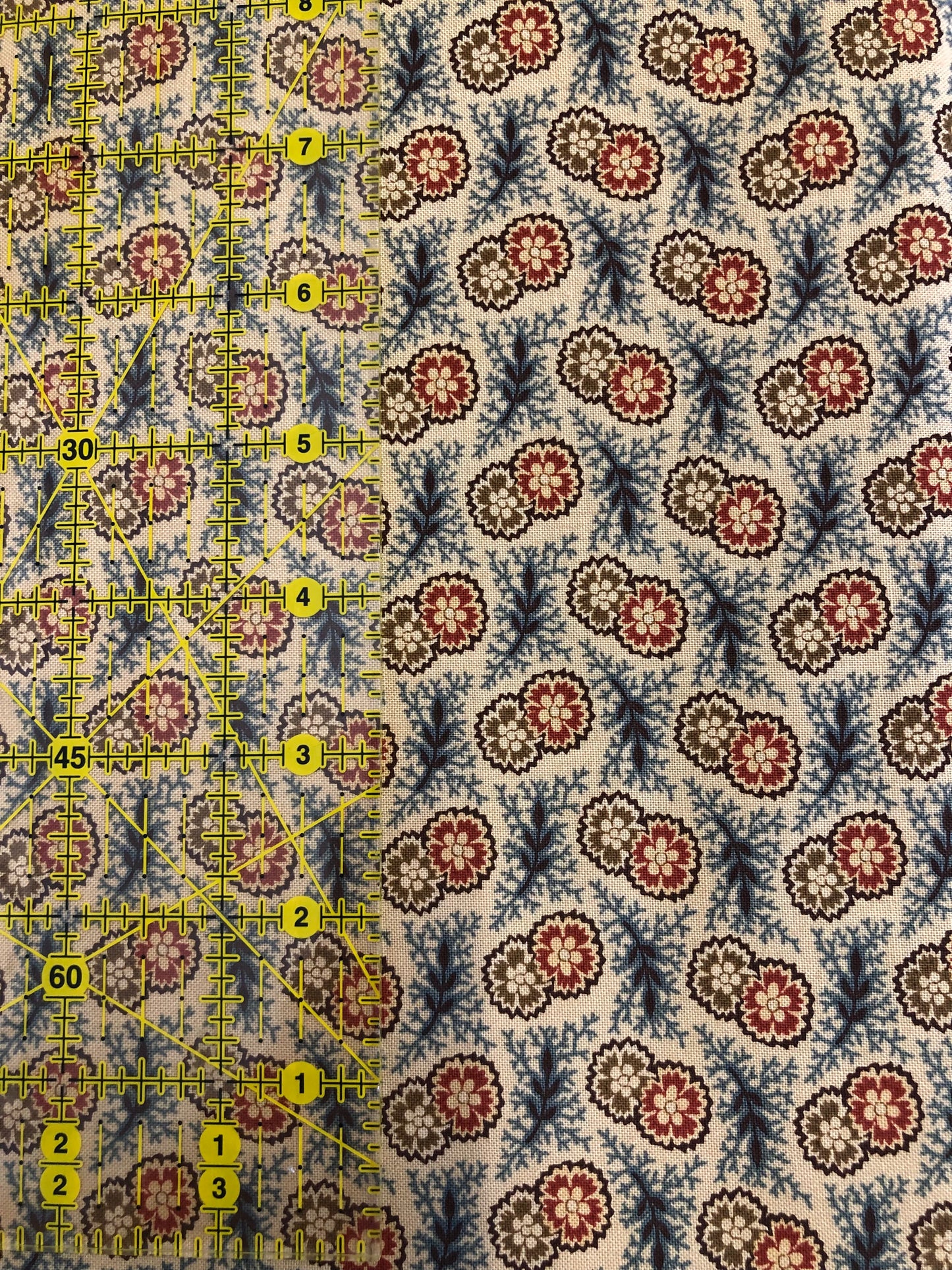 Jo Morton fabric, red, cream and blue paisley medallions on cream, beside a ruler in inches