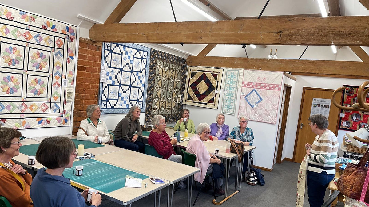 A class in the studio at Village Fabrics, with students round the tables and quilts on the walls