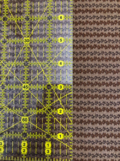Jo Morton fabric, rows of small brown leafy vines on a pale ground, beside a ruler in inches