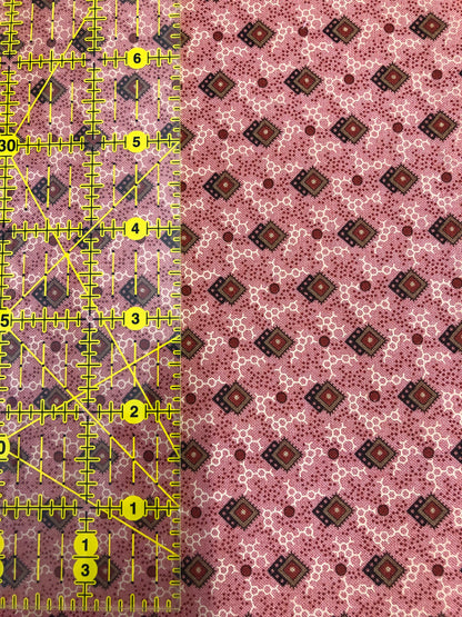 Jo Morton fabric, small brown diamonds and dots on pink, beside a ruler in inches