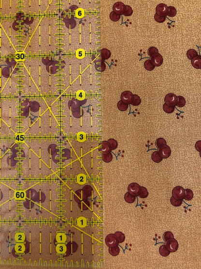 Jo Morton fabric, red cherries on caramel tan, beside a ruler in inches