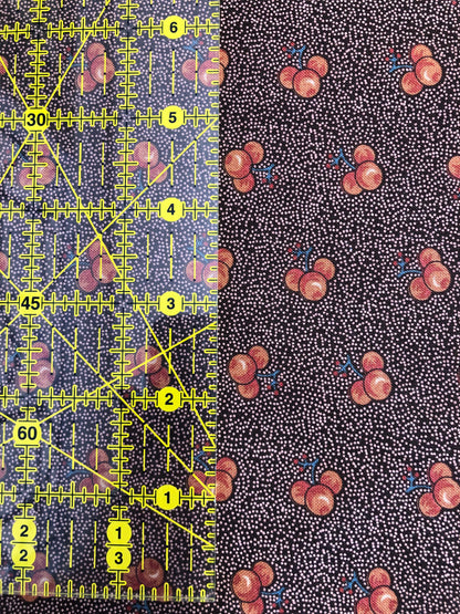 Jo Morton fabric, red cherries on brownish plum speckle, beside a ruler in inches