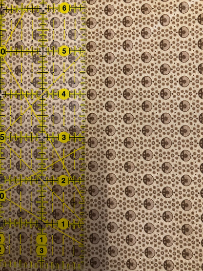 Jo Morton fabric, small brown rings and dots on tan, beside a ruler in inches