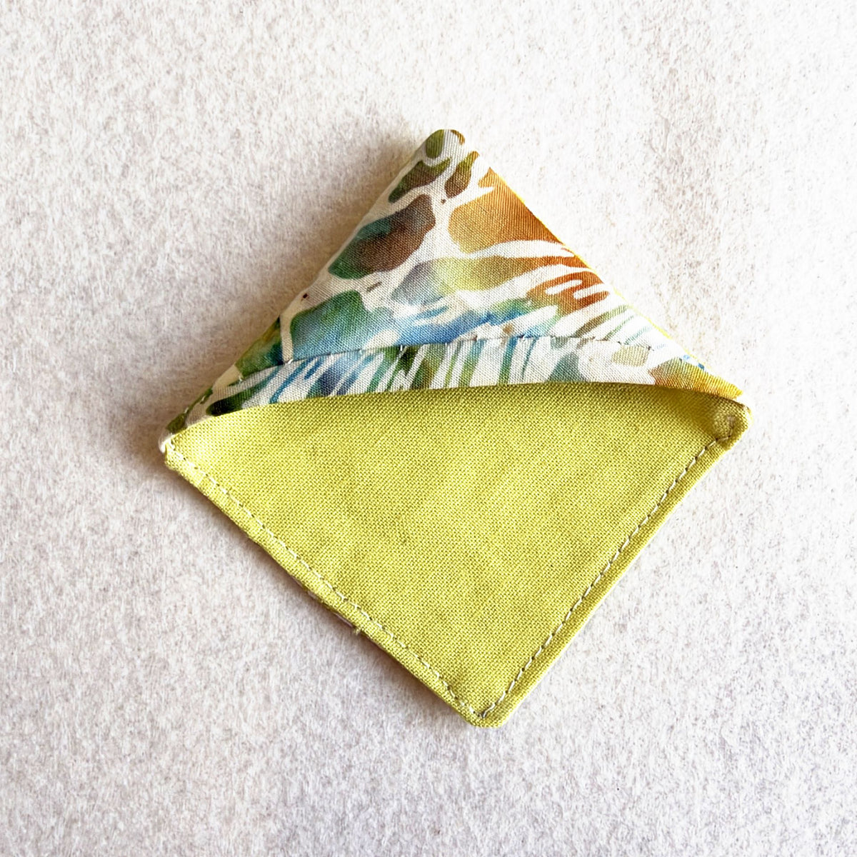 A finished Bookmark Corner: a folded fabric triangle that slips over the corner of a page