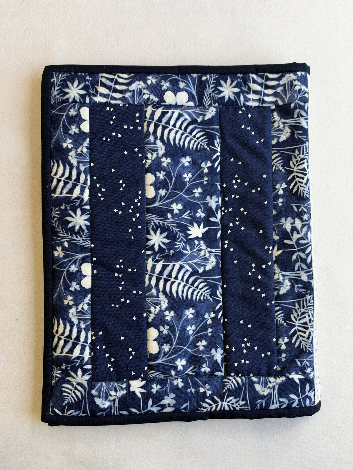 The back of the Boro Folder Cover: a leafy navy print between two dark navy strips