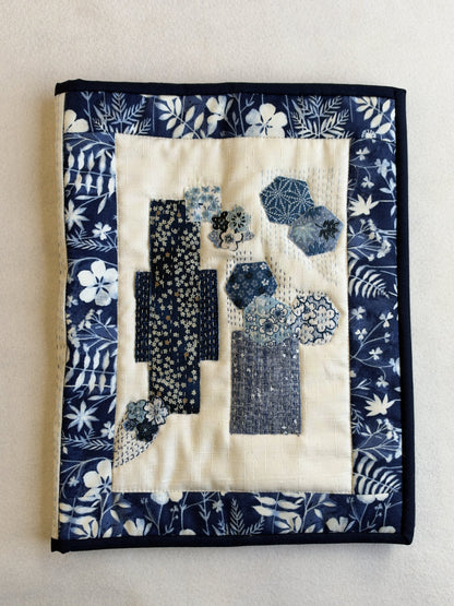 The front of the blue Boro Folder Cover: patches of navy prints and printed hexagons on cream, with hand running stitch