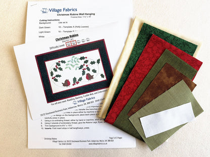 What's in the Christmas Robins Wall Hanging kit: the printed instructions and fabrics in cream, greens, red, brown and white
