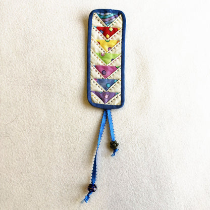 Flying Geese Bookmark: a quilted bookmark with rainbow flying geese, blue binding and a beaded ribbon tail