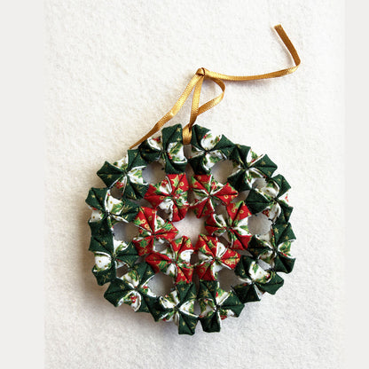Mini Christmas Wreath made from the kit: a small folded fabric wreath in green, red and cream Christmas prints with a gold hanging ribbon